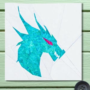 May include: A teal and turquoise dragon head design on a white background. The dragon's eye is a bright pink, and the design is made of geometric shapes. The artwork is on a square canvas.