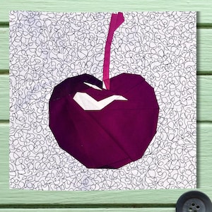 May include: A purple fabric cherry with a white stem on a white background with black squiggly lines.