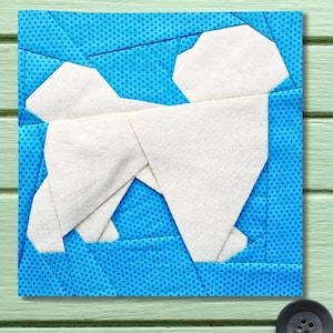 May include: A square fabric block featuring a white dog silhouette against a blue dotted background. The dog is constructed from geometric shapes, giving it a modern, minimalist appearance. The block is likely part of a larger quilting project.