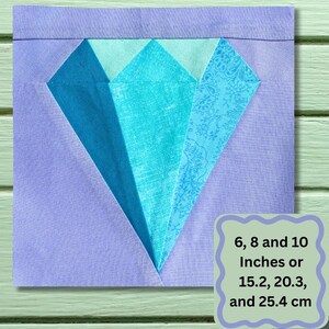 May include: A square fabric block featuring a diamond design in shades of blue and turquoise, set against a lavender background. The diamond is composed of several fabric pieces. The image includes text indicating sizes of 6, 8, and 10 inches.
