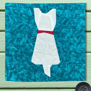 May include: A white dress with a red ribbon around the waist, on a teal blue background.