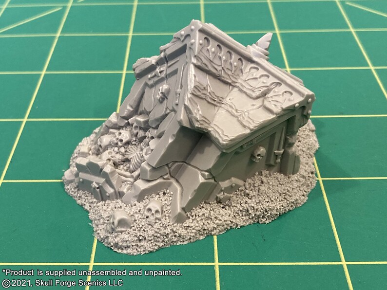 K&ouml;nnte beinhalten: Ein graues, detailliertes Miniaturmodell eines zerst&ouml;rten Geb&auml;udes mit Sch&auml;deln und Knochen, die umherliegen. Das Modell ist aus Kunststoff und unlackiert.