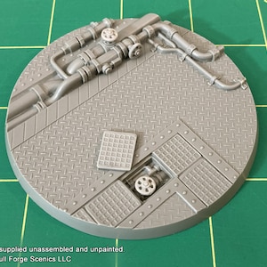 May include: A grey plastic model of a round base with a metal grate pattern and pipes and valves. The base is designed for use in tabletop games and miniature wargaming.