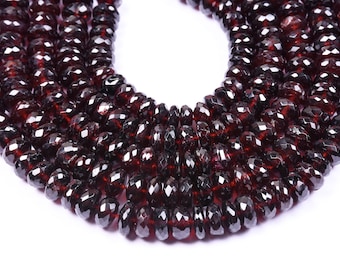 May include: A strand of dark red faceted gemstone beads. The beads are round and have a smooth, polished finish.