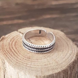 Puede incluir: Un anillo de dedo del pie de plata con tres bandas de detalle texturizado.