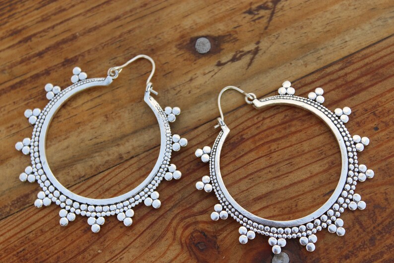 May include: A pair of silver hoop earrings with a beaded design. The earrings have a circular shape and are decorated with small, round beads.