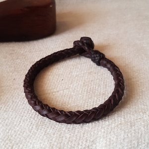 Puede incluir: Un brazalete trenzado de cuero marr&oacute;n con cierre de nudo.