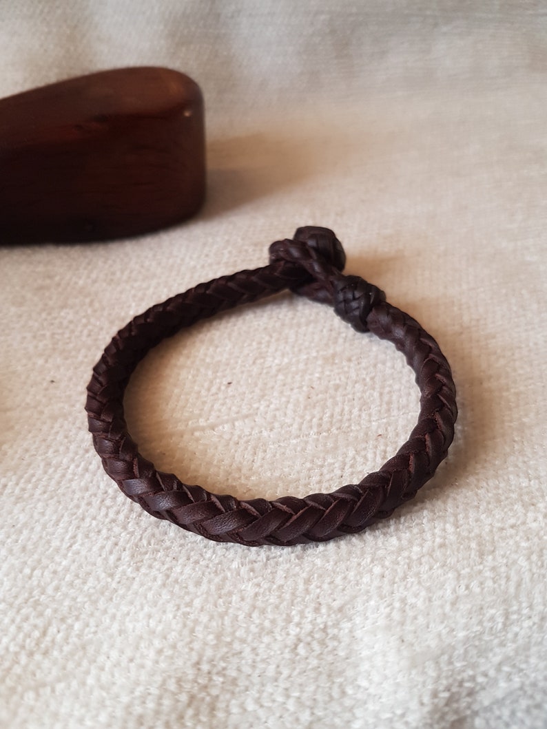 Puede incluir: Un brazalete trenzado de cuero marr&oacute;n con cierre de nudo.