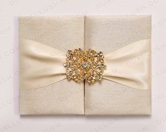 Invitación de boda de bolsillo en satén color marfil: Folio de seda con broche de diamantes de imitación.