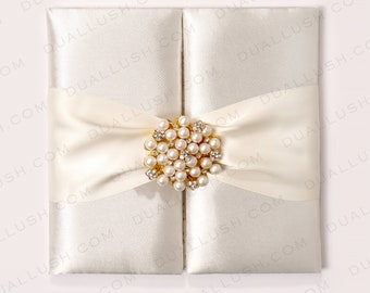 Juego de invitaciones de boda en folio de satén blanco: broche de perlas, tarjeta con inserto metalizado.