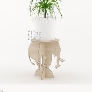 May include: A wooden plant stand shaped like an elephant with a round top. The stand is made of plywood and has a natural wood finish. The stand is designed to be assembled with a few screws. The stand is perfect for displaying a small plant or other decorative items.