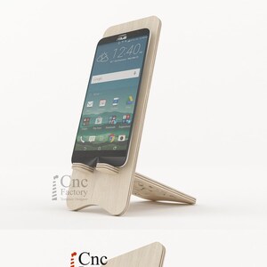 Op de afbeelding: Een houten telefoonstandaard met een decoratief uitgesneden ontwerp. De standaard is gemaakt van licht hout en heeft een eenvoudig, modern ontwerp. De standaard is ontworpen om een smartphone in een verticale positie te houden.