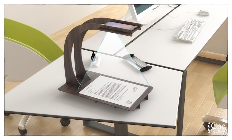 Op de afbeelding: Een houten standaard met een gebogen arm die een smartphone boven een vel papier houdt. De standaard staat op een wit bureau met een toetsenbord en een muis.