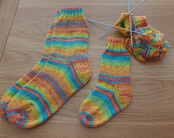May include: Two pairs of colorful striped socks in shades of yellow, orange, blue, and pink. The socks are knitted and have a ribbed texture.