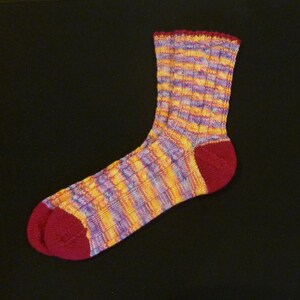 May include: A colorful striped sock with a red heel and toe. The sock is made of a soft, knitted fabric and has a subtle texture.