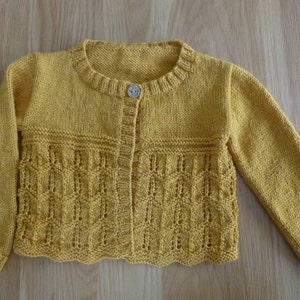 Può includere: Un cardigan di maglia giallo con chiusura a bottone e un delicato motivo a pizzo.