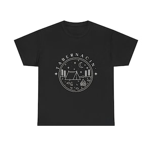 Może przedstawiać: Czarny t-shirt z białym graficznym wzorem przedstawiającym scenę kempingową w okręgu. Projekt zawiera namiot, drzewa, ognisko i napis "TABERNACIN". Koszulka ma okrągły dekolt.