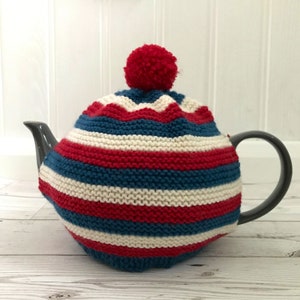 May include: A red, white and blue striped knitted teapot cosy with a red pom-pom on top.
