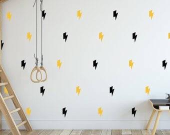 May include: A white wall with black and yellow lightning bolt decals. A wooden ladder, a wooden swing set with rings, and a wooden desk and chair are in the room. A black chalkboard with the text "Home of the Cool Kids" is on the wall.