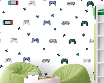 May include: A white wall with a repeating pattern of video game controllers and game consoles. The wall is decorated with black crosses, circles, and squares. There are two green beanbag chairs in front of the wall, and a white round coffee table between them. A white loft bed with a green mattress is on the right side of the image. A white desk with a green drawer unit is in the lower right corner of the image. A white chair with a black seat is in front of the desk.