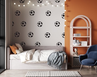 Peut inclure: Une chambre à coucher avec un lit blanc, un fauteuil bleu et une bibliothèque blanche avec des étagères orange. Le mur derrière le lit est blanc avec des autocollants de ballon de football noirs. Le mur derrière la bibliothèque est orange.