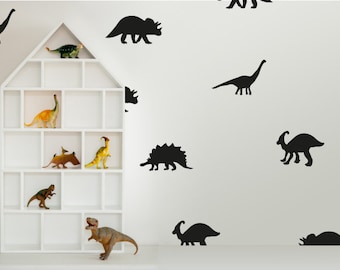 May include: A white shelf unit with multiple compartments, filled with toy dinosaurs. The wall behind the shelf is decorated with black dinosaur silhouettes.