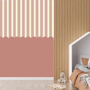 Op de afbeelding: Een muurschildering met een bovenste gedeelte met verticale crème en oudroze strepen en een effen oudroze onderste gedeelte met een geschulpte rand. De muurschildering is geplaatst op een muur naast een houten lattenwand en een bed.
