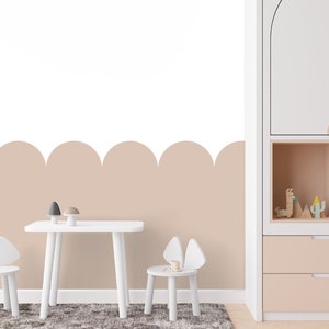 Op de afbeelding: Een witte tafel en stoelen met een lichtbruine gegolfde rand aan de muur. De tafel en stoelen staan in een kinderkamer met een witte kast met planken en lades.