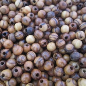 May include: A close-up of a pile of brown and black wooden beads with a hole in the center of each bead. The beads are round and have a natural wood grain pattern.
