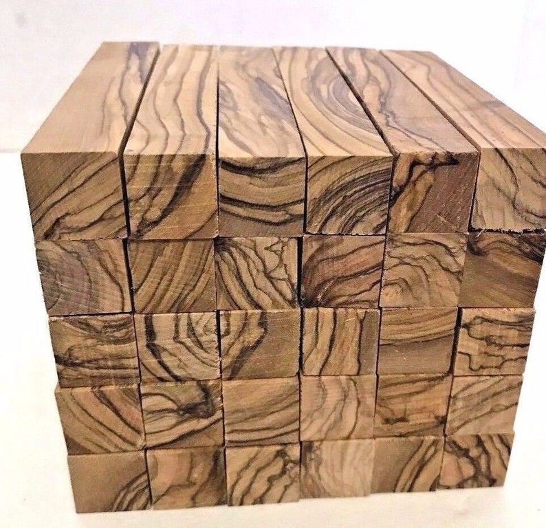 May include: A stack of 36 square wooden blocks, each with a unique wood grain pattern. The blocks are made of olive wood and are approximately 1 inch by 1 inch by 3 inches in size.