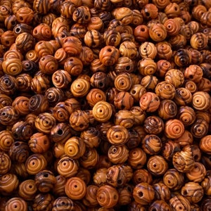 May include: A large pile of wooden beads with a swirl pattern. The beads are a mix of brown and orange colors.