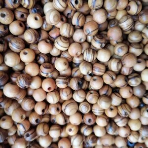 May include: A large pile of brown wooden beads with dark brown stripes. The beads have a hole in the centre for stringing.