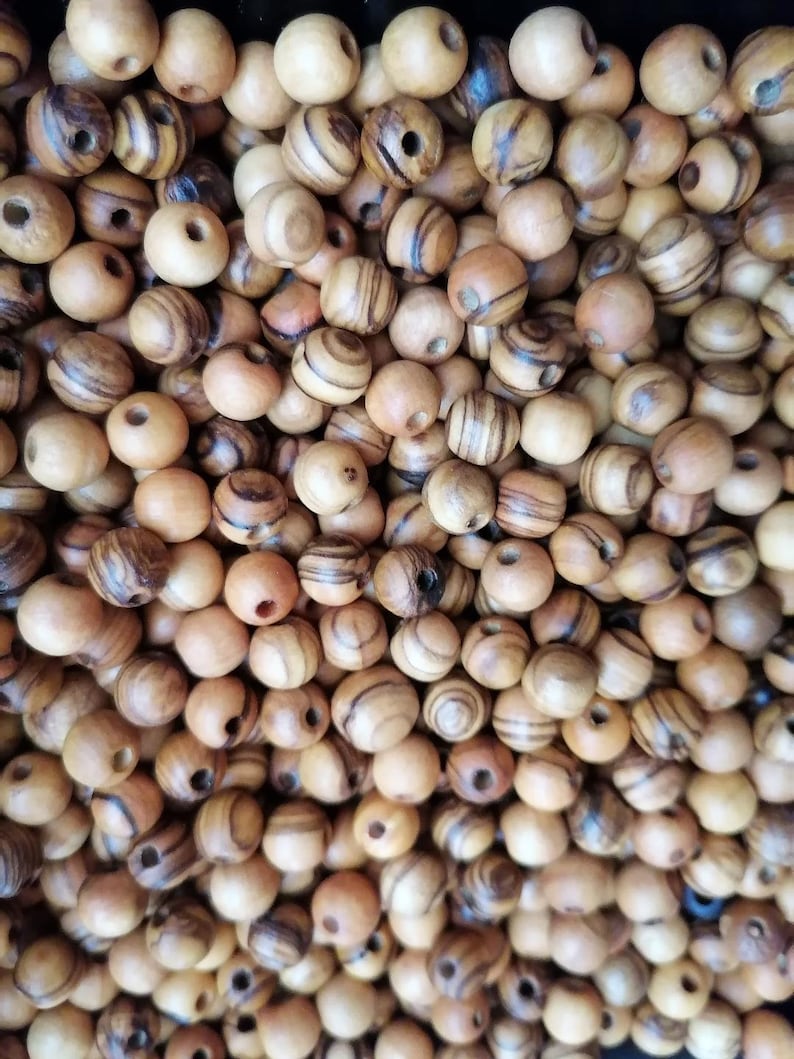 May include: A large pile of brown wooden beads with dark brown stripes. The beads have a hole in the centre for stringing.