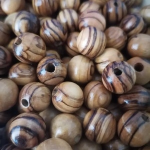 May include: A close-up of a pile of wooden beads. The beads are round and have a natural wood finish with brown and tan stripes.