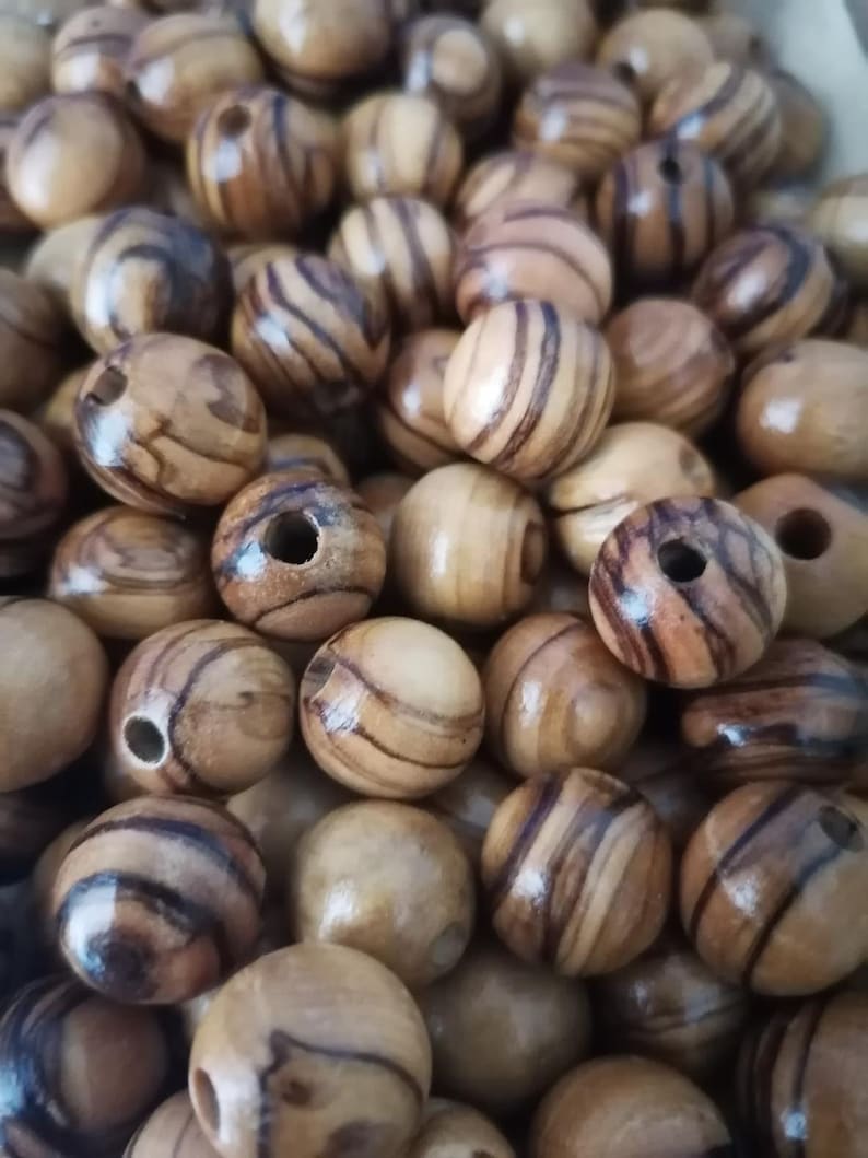 May include: A close-up of a pile of wooden beads. The beads are round and have a natural wood finish with brown and tan stripes.