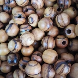 May include: A close-up of a pile of round wooden beads with dark brown stripes. The beads have a natural wood finish and are ideal for crafting.