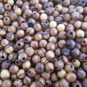 May include: A close-up of a pile of wooden beads. The beads are brown and have dark brown stripes. They are round and have a hole in the center.