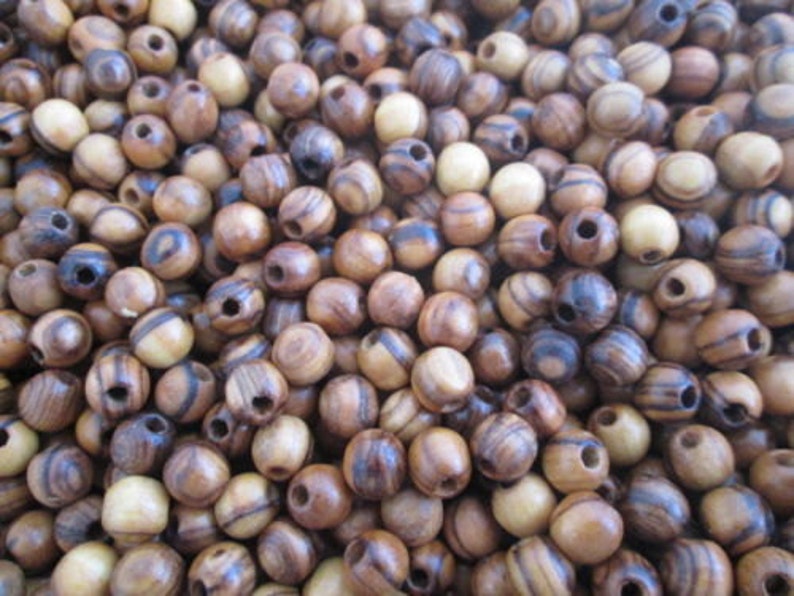 May include: A close-up of a pile of wooden beads. The beads are brown and have dark brown stripes. They are round and have a hole in the center.