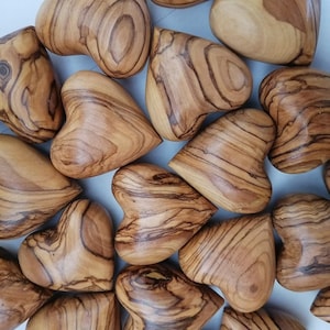 May include: A collection of wooden heart-shaped ornaments, each with a unique grain pattern and a warm brown color.