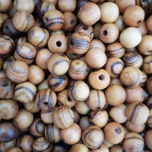 May include: A close-up of a pile of wooden beads with brown and white stripes. The beads are round and have a hole in the centre.