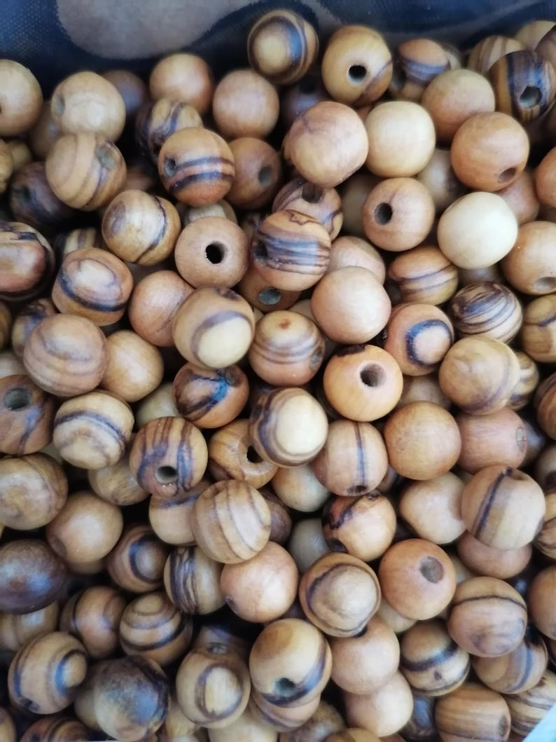 May include: A close-up of a pile of wooden beads with brown and white stripes. The beads are round and have a hole in the centre.
