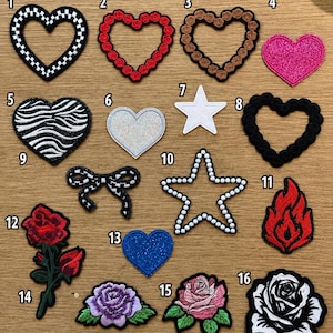 May include: A collection of sixteen embroidered patches featuring various shapes and designs, including hearts, stars, a bow, a flame, and roses. The patches are numbered one through sixteen and display diverse patterns like checkerboard, glitter, and floral motifs.
