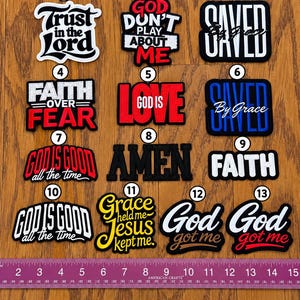 May include: Thirteen embroidered patches with religious text, numbered one through thirteen, arranged in rows. A purple ruler at the bottom shows measurements in inches, with the patches ranging from approximately 2 to 4 inches in width.