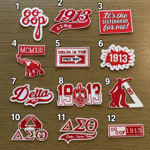 May include: A collection of twelve red and white embroidered patches featuring Delta Sigma Theta sorority themes. Designs include the text 'oo-oop', '1913', 'It's the SISTERHOOD for me!', 'MCMXIII' with an elephant, 'DELTA IS THE ONLY WAY', and Greek letters.