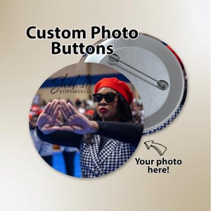 May include: A round custom photo button featuring a person wearing a red beret, black sunglasses, and a black and white houndstooth blazer, making a triangle hand gesture. The text Custom Photo Buttons and Your photo here! are visible.