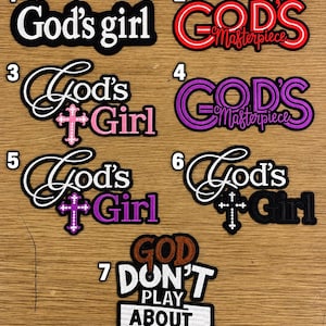 May include: A collection of seven embroidered patches featuring text and religious symbols. Designs include phrases like God's girl, God's Masterpiece, and God Don't Play About Me, rendered in various fonts, colors, and cross motifs on black fabric.