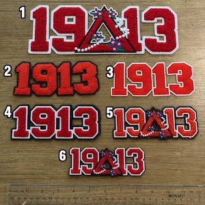 May include: Six red and white embroidered patches featuring the number 1913, with some designs incorporating a red triangle, purple flowers, and white pearls. A 12-inch ruler is positioned at the bottom to show the scale of the various patch sizes.
