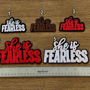 May include: Five embroidered patches labeled 1 through 5, each featuring the text 'she is FEARLESS'. The patches come in white, brown, and red color variations. A Westcott ruler is positioned below, showing measurements up to 12 inches.