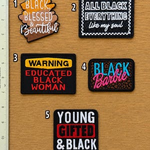 May include: Five rectangular and shaped embroidered patches with text. Patch 1 says BLACK BLESSED & Beautiful. Patch 2 says ALL BLACK EVERYTHING like my soul. Patch 3 says WARNING EDUCATED BLACK WOMAN. Patch 4 says BLACK Barbie. Patch 5 says YOUNG GIFTED & BLACK.