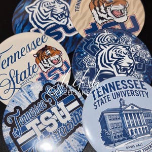May include: A collection of six circular pin-back buttons featuring Tennessee State University branding. Designs include tiger mascots, the TSU logo, and an illustration of Davis Hall with the text Home of the Tigers, Nashville, TN.